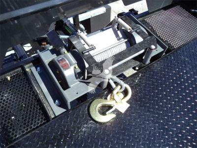 Isuzu FTR rollback truck hydraulic winch mechanism with hook, mounted on a diamond plate platform.