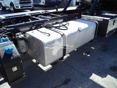 Isuzu FTR rollback truck fuel/water tanks and underbody components visible in a yard.