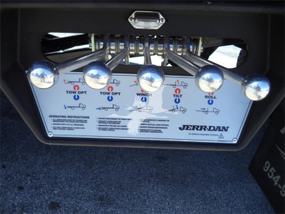 Truck tow/boom control panel with multiple levers labeled TOW OPT, WINCH, TILT, ROLL showing control handles on a JERR-DAN rollback unit.