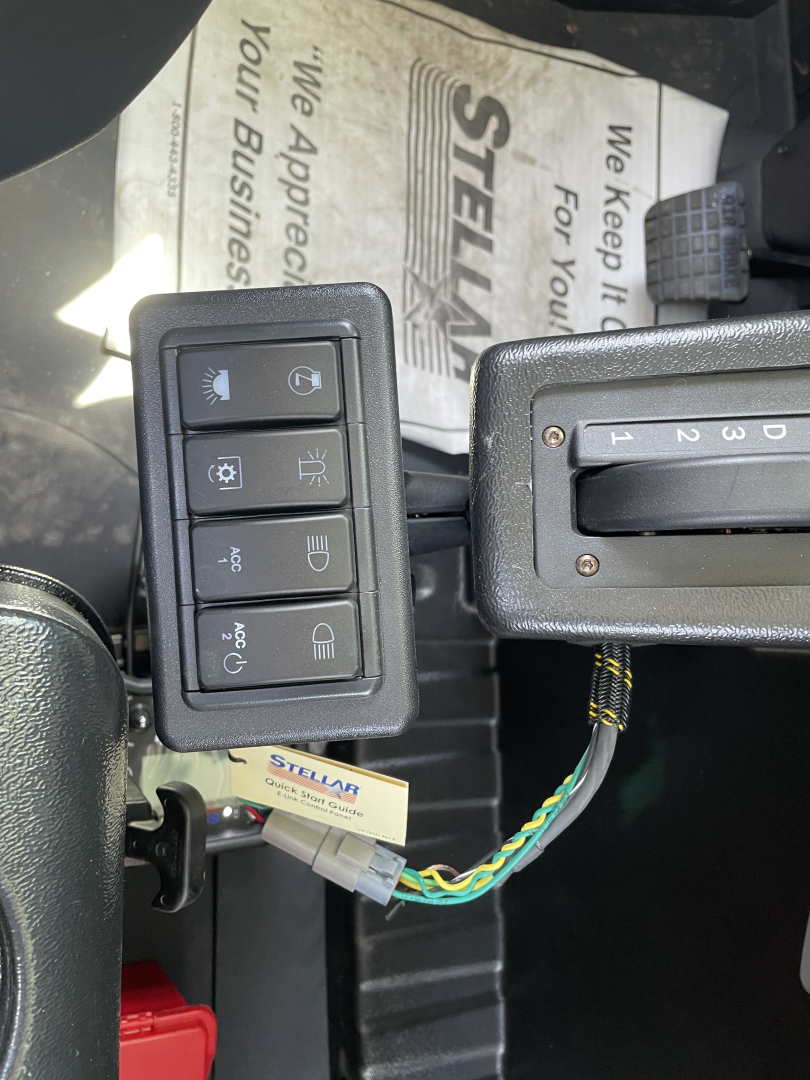 Control panel with multiple rocker switches and a gear shifter in a Mack MD6 truck cabin showing wiring harness and dashboard area.