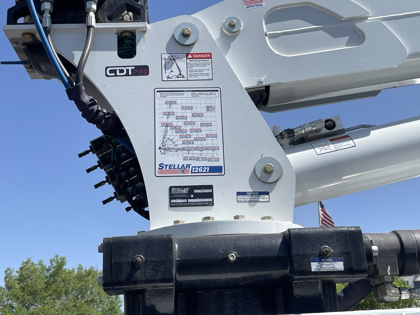 Service/utility truck component with labels: CDT PRO, Stella 12621, warning labels, and hydraulic arm; visible tags and charts on white metal surface.