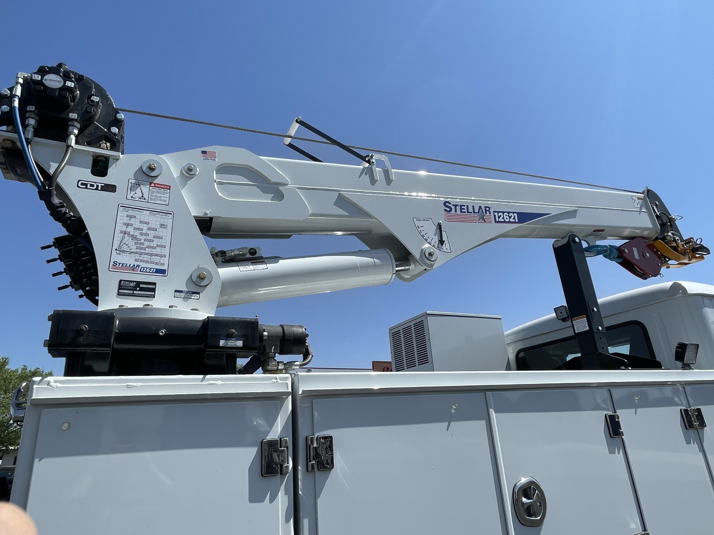 Stellar crane arm on a Mack MD6 service truck with control labels and hydraulic components visible on the boom.