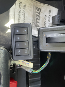 Control panel with multiple rocker switches and a gear shifter in a Mack MD6 truck cabin showing wiring harness and dashboard area.