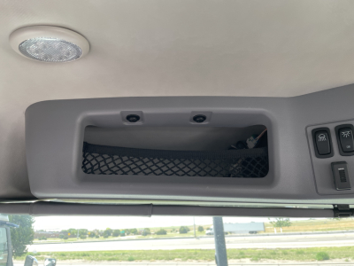 Cab interior ceiling with overhead storage pocket and control panel on right, view through windshield.