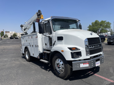 Front-right view of a white 2026 Mack MD6 service truck with utility compartments and a mounted crane; visible text includes MACK on grille and no other legible labels.