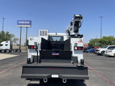 Back of a service/utility truck with a large flatbed and crane; rear doors open; tailgate and stows; text on small plate and branding on bumper.