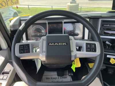 Mack MD6 dashboard steering wheel with 'MACK' logo on center; instrument cluster and touch display visible; control buttons on steering wheel and dash; cab interior details.