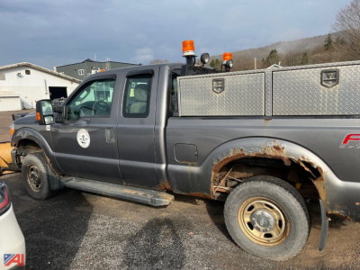 Ford F-250 Super Duty extended cab pickup with plow truck showing side view, rust on rear fender, dual orange beacon lights, and diamond-plate utility box in bed.