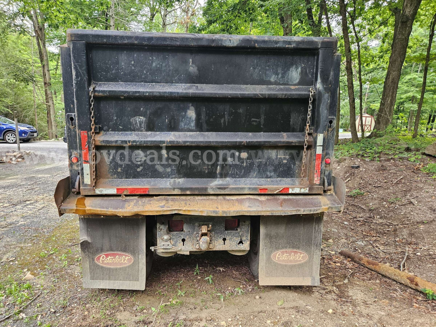 Dump truck bed of a 2005 Peterbilt 335 rear view showing tailgate, mud flaps with Peterbilt logos, and hitch area.