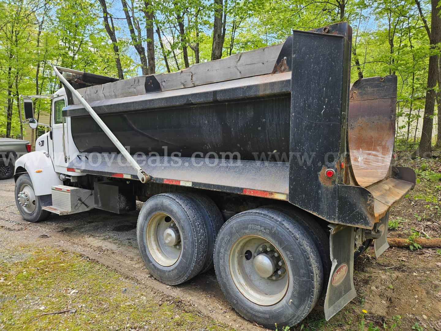 Peterbilt 335 dump truck side view showing heavy-duty dump bed and dual rear axles with wheels, used vehicle for sale.