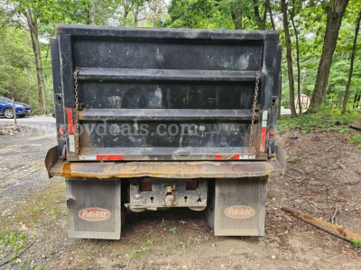 Dump truck bed of a 2005 Peterbilt 335 rear view showing tailgate, mud flaps with Peterbilt logos, and hitch area.