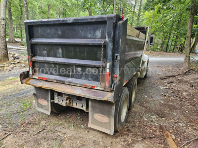 Dump truck rear view showing Peterbilt 335 dump bed, dual rear wheels, mud flaps, and taillights.