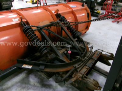 Dump truck equipment with orange snow plow blade and suspension arms in view.