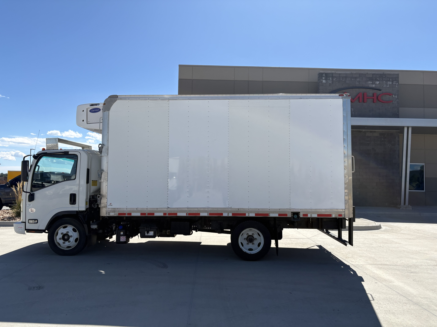 Refrigerated box truck side view showing white cargo box on Chevrolet W4500 with refrigeration unit visible above cab