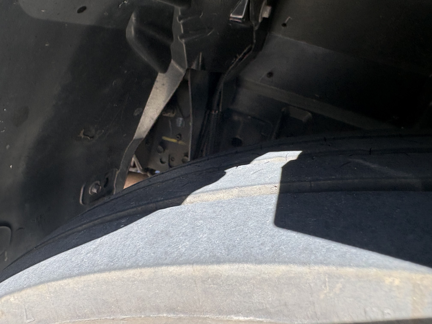 Truck wheel well area with suspension components and frame under a refrigerated 2020 Chevrolet W4500; partial view of tire and undercarriage.