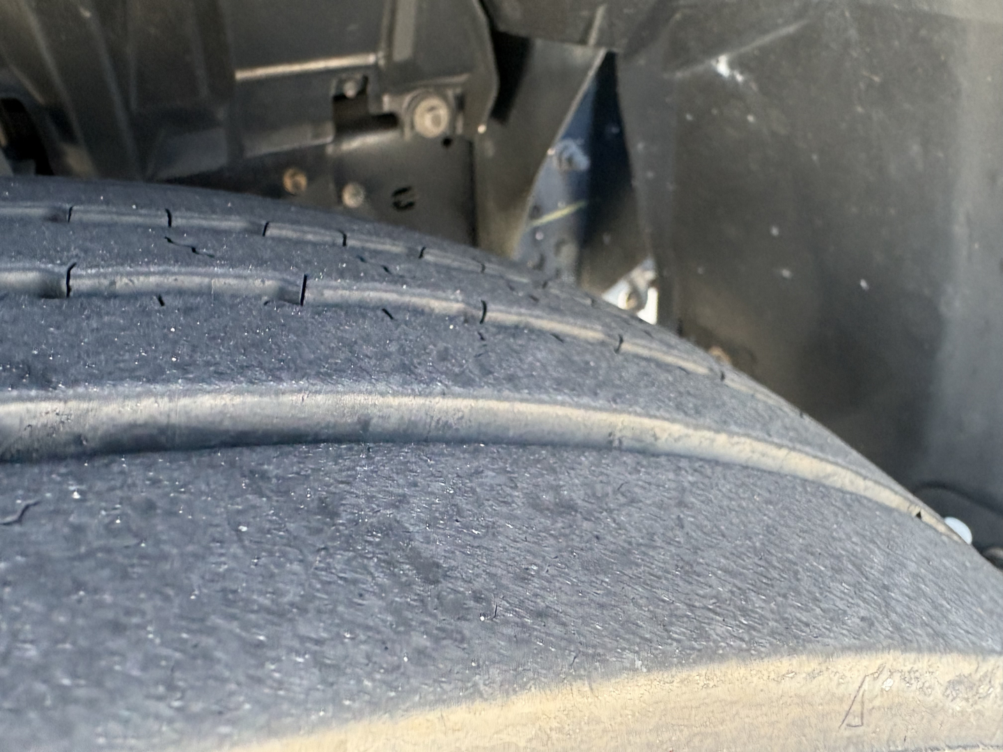 Truck wheel/tire close-up undercarriage with vehicle body and chassis visible.