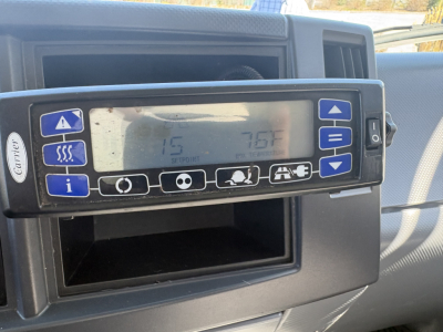 Vehicle instrument panel showing a Caterpillar climate control unit with digital display and various control icons.