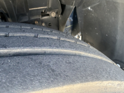 Truck wheel/tire close-up undercarriage with vehicle body and chassis visible.