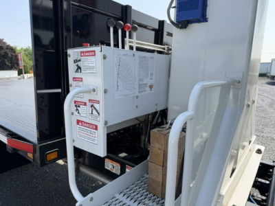 Freightliner M2-106 crane truck side panel with control box and warning labels visible.