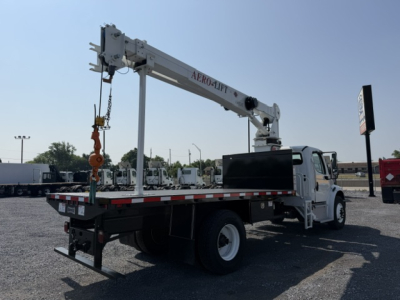 Truck-mounted crane on a white Freightliner M2-106 bed with a folding crane arm labeled ALRO-AFT, extended over the rear with rigging; VIN plate and stock number visible in background.