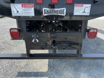 Rear view of a Freightliner M2-106 crane truck showing bumper, taillights, hitch, and warning labels with a knapheide spare area.