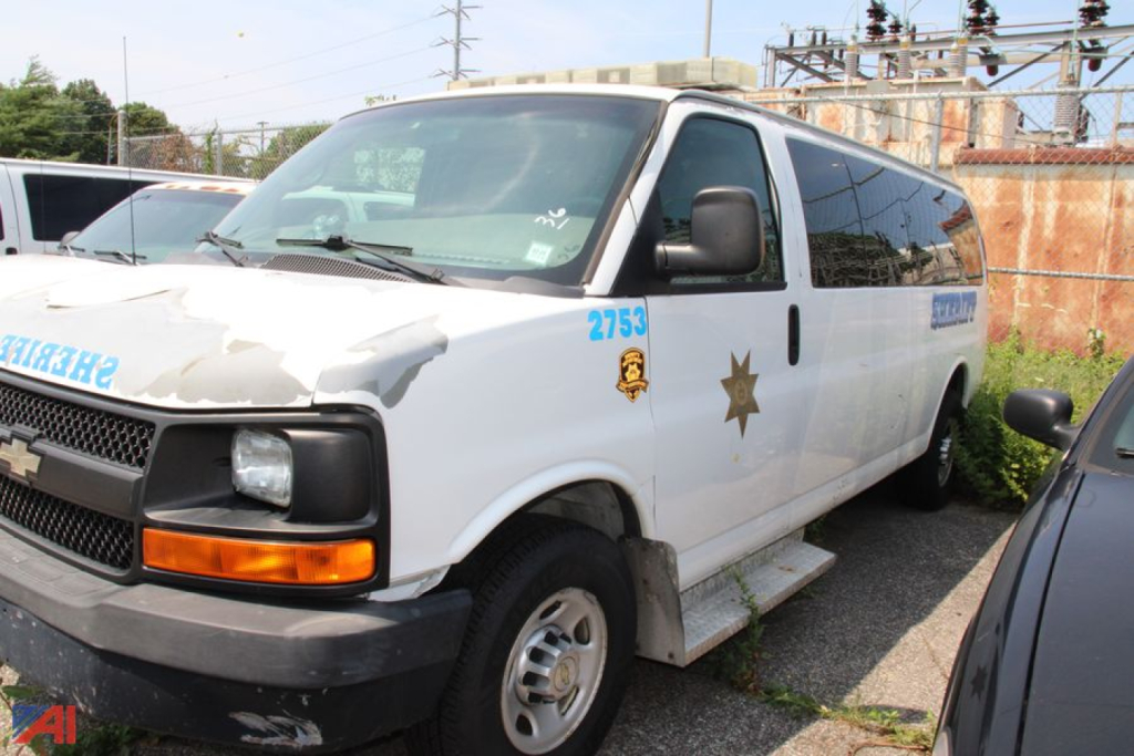 Front-left view of a white 2010 Chevrolet Express LS3500 van with police markings, star badge, and blue numbers on the door. Cargo van/utility vehicle in a lot.