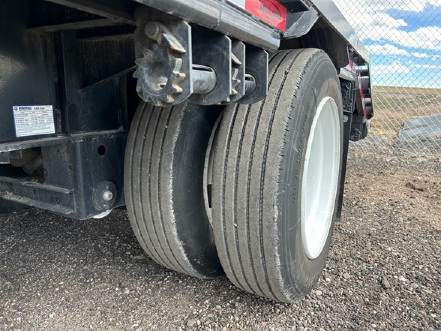Dual rear wheels of a used drop deck trailer with rugged tires and white rims, part of a Dura Haul steel drop deck trailer.