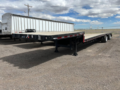 Trailer: 2025 Dura Haul steel drop deck, long flatbed with dual rear axles, used condition, side rails and reflective tape visible.