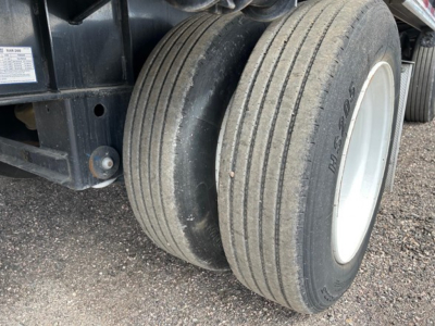 Dual rear tires of a drop deck trailer showing tread and sidewall markings