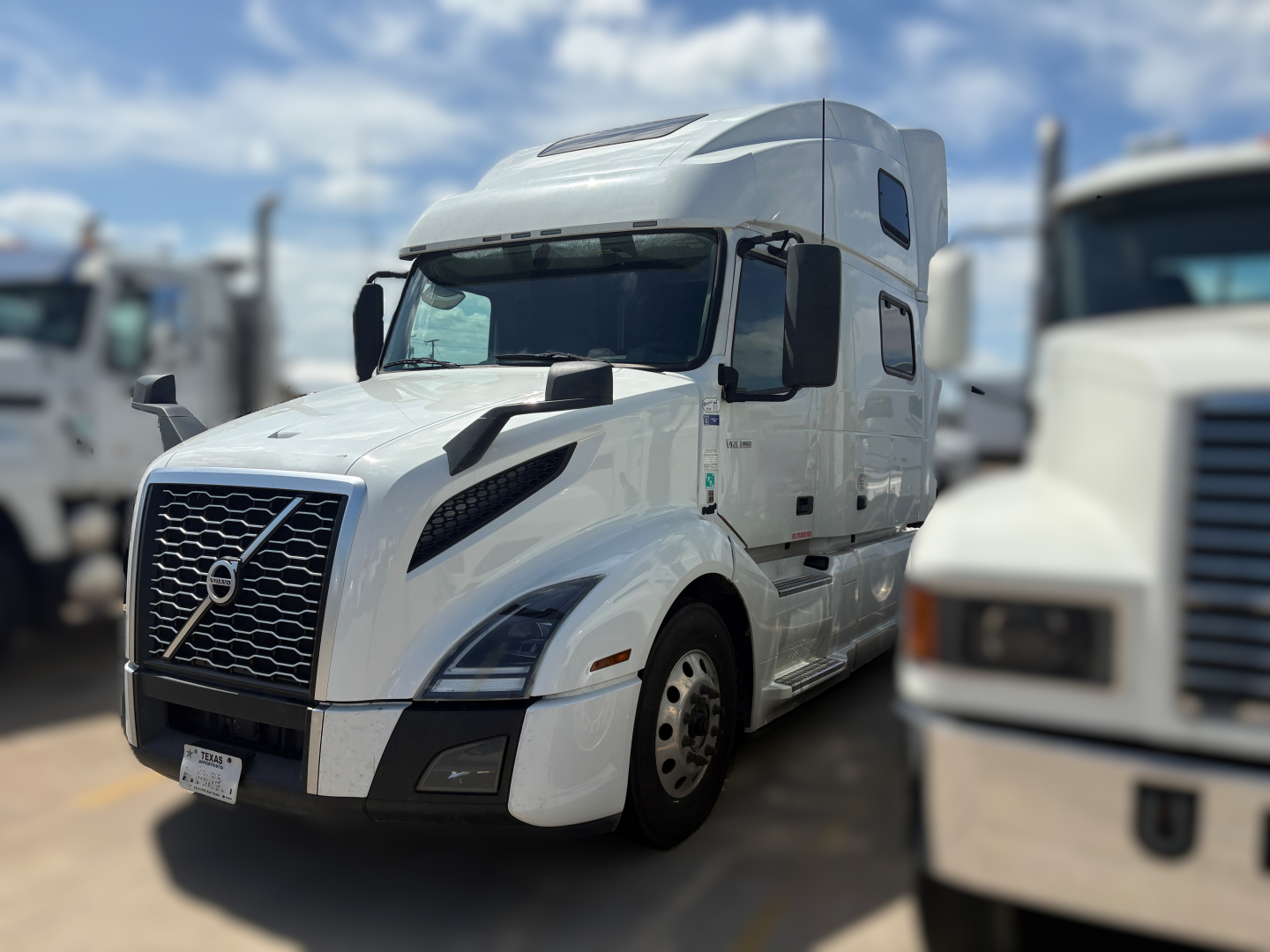 Volvo VNL64T860 truck in white, front view showing grille, headlights, and side mirror, with sleeper cab and windows.
