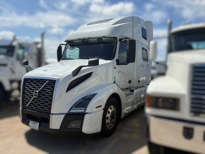 Volvo VNL64T860 truck in white, front view showing grille, headlights, and side mirror, with sleeper cab and windows.