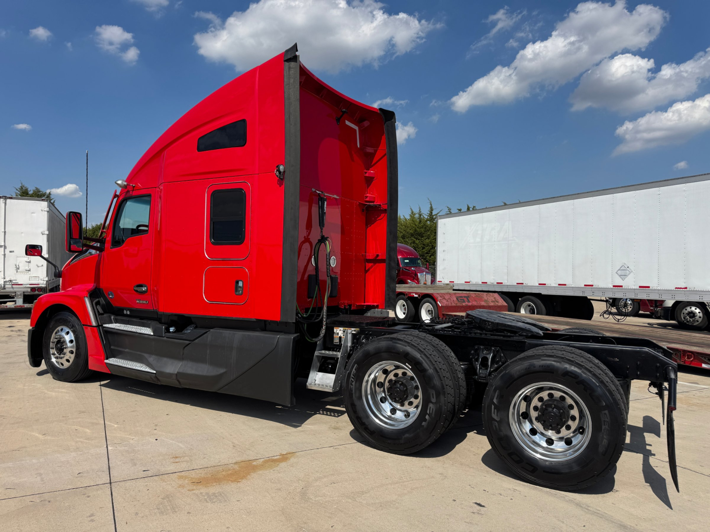 Kenworth T680 cab and chassis side view showing red sleeper cab and dual rear axles with chrome wheels.