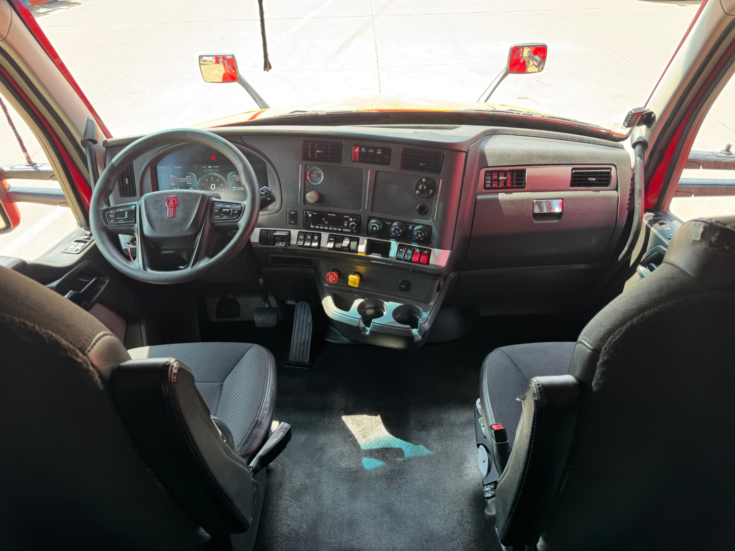Kenworth T680 cab interior showing dashboard and steering wheel with center console and storage compartments.