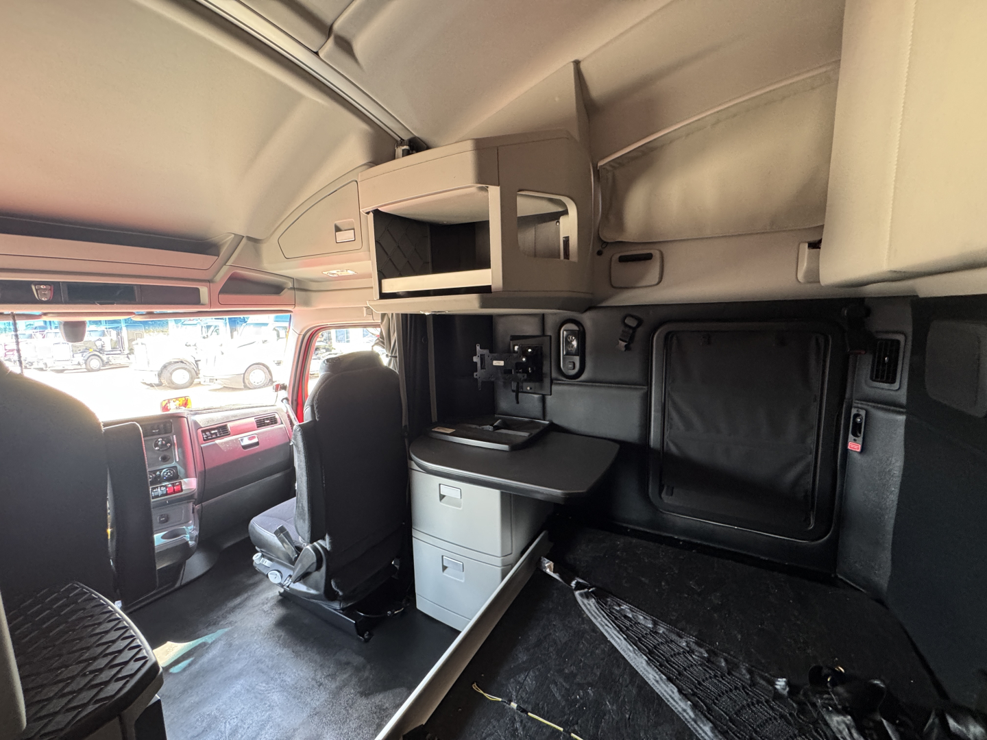 Kenworth T680 cab interior with sleeper area, side cabinetry, and dashboard visible; includes overhead storage and control panels.