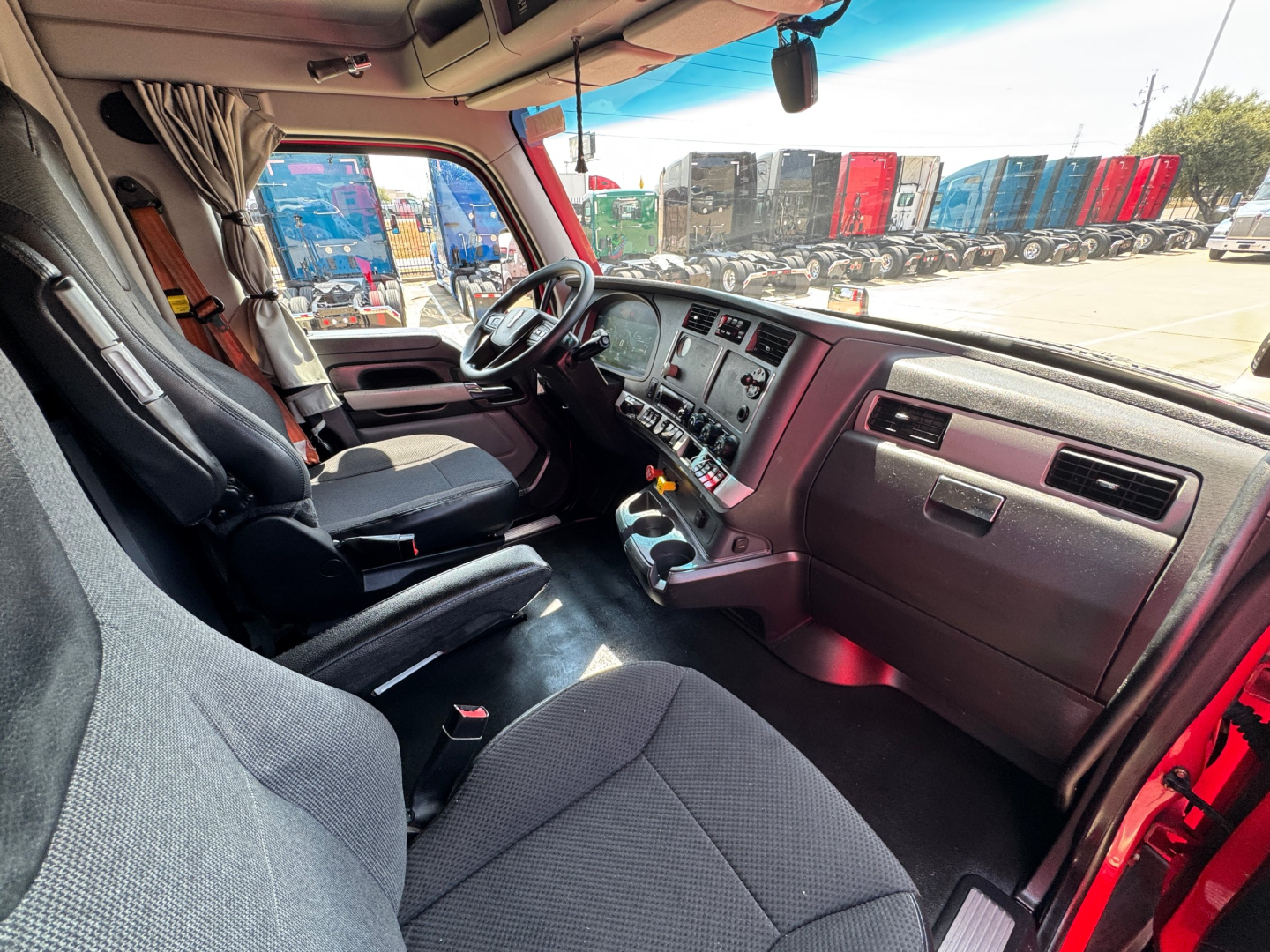 Kenworth T680 truck interior showing driver seat, dashboard with instrument panel, steering wheel, and center console.