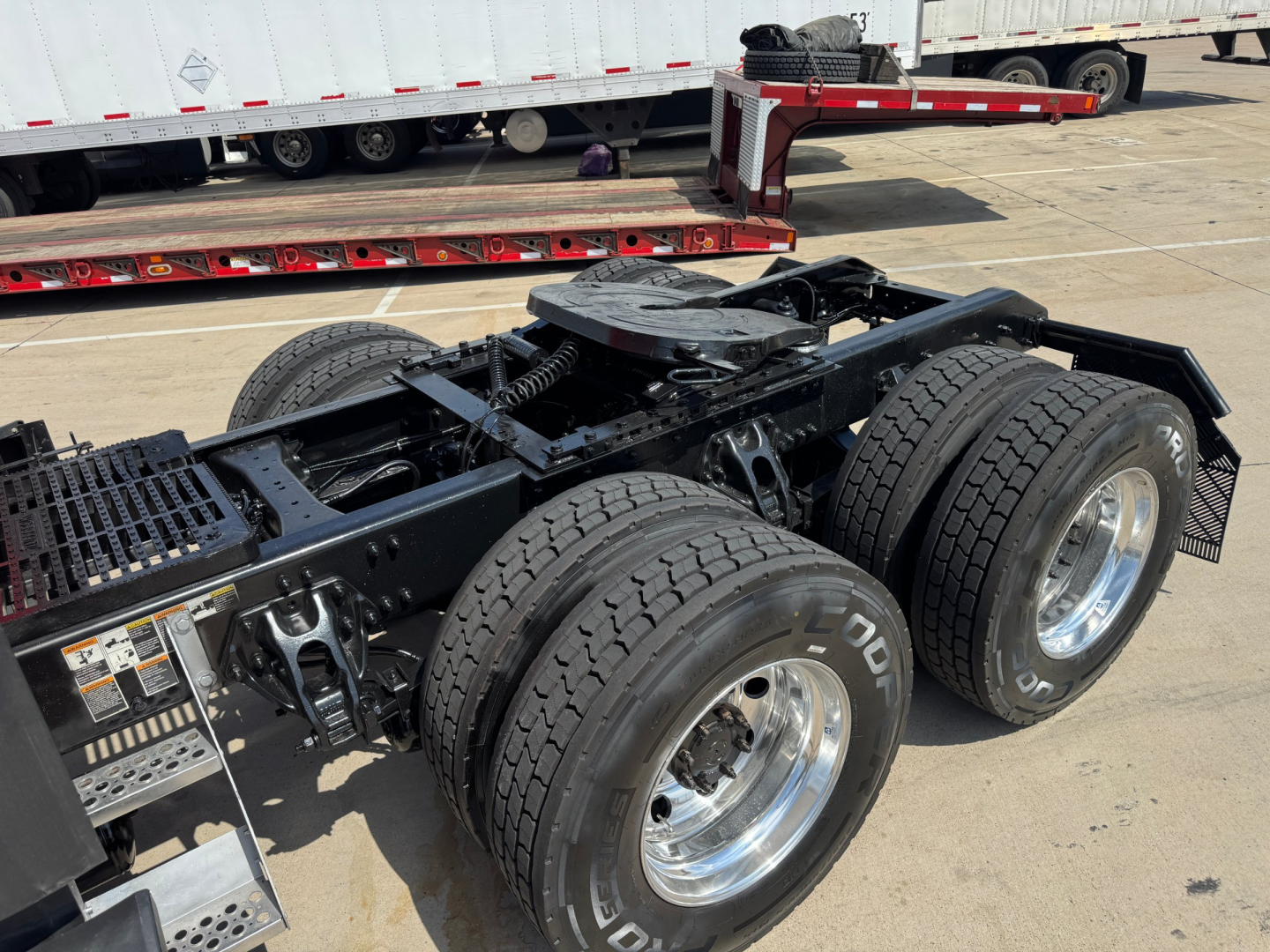 Kenworth T680 tractor rear chassis showing dual rear axles and fifth-wheel mount with wheels and tires visible.
