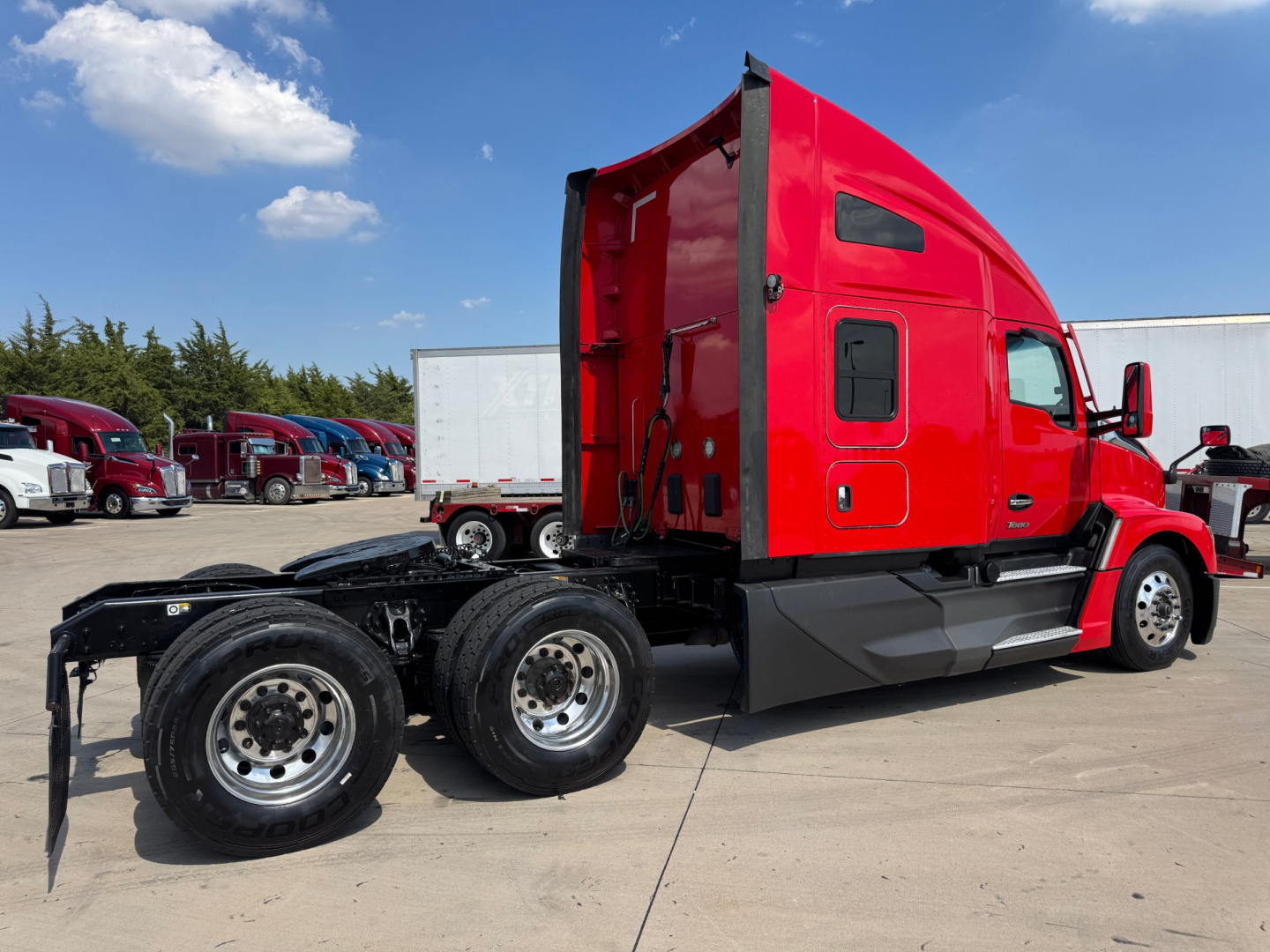 Kenworth T680 tractor with bright red cab side view showing chassis and rear wheels