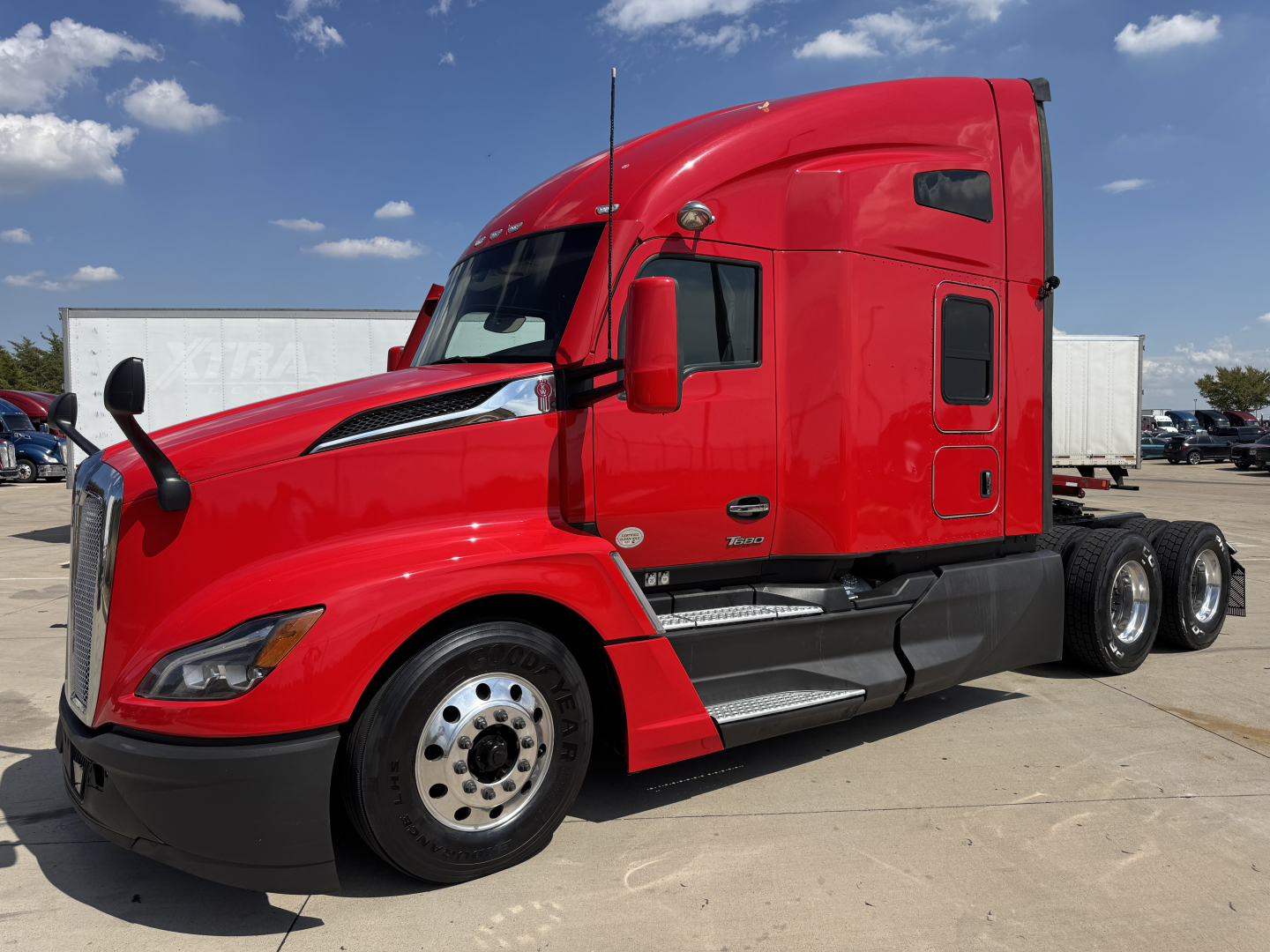 Kenworth T680 sleeper cab side view in red with three axles, front and rear wheels visible, trucking scene.