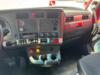 Kenworth T680 cab interior dashboard view showing steering column, control switches, HVAC vents, gauges, cup holders and glove compartment.