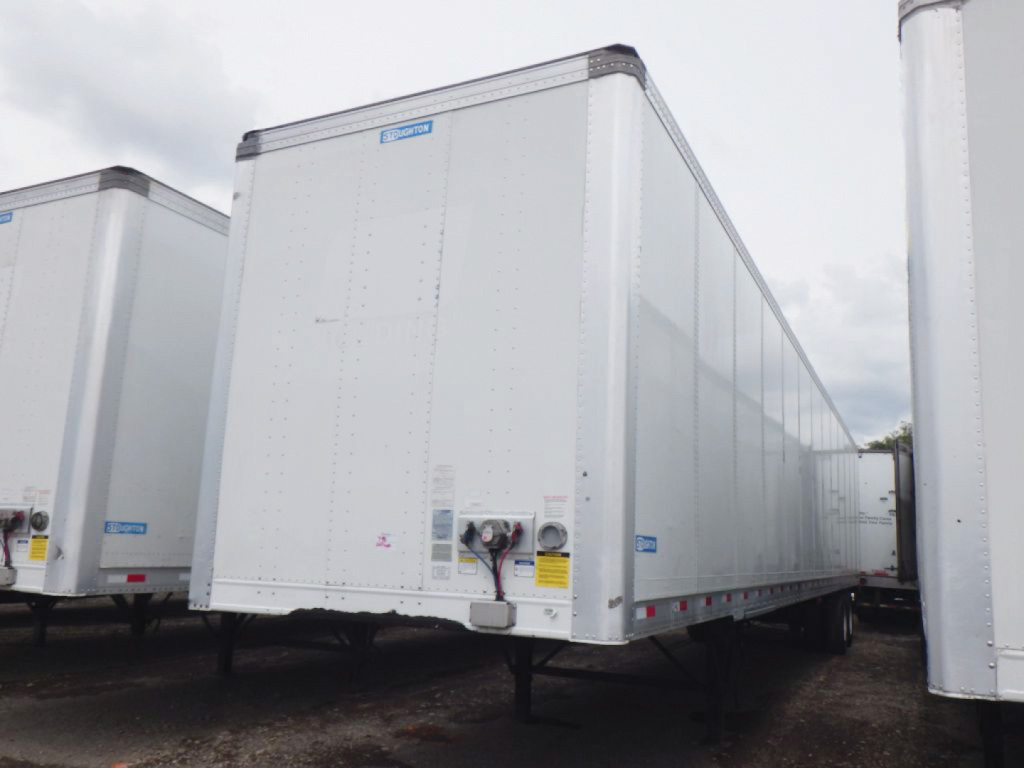 Trailer side view showing a white Stoughton plate van with lift-post and rear decals, front jack stands, and undercarriage visible.
