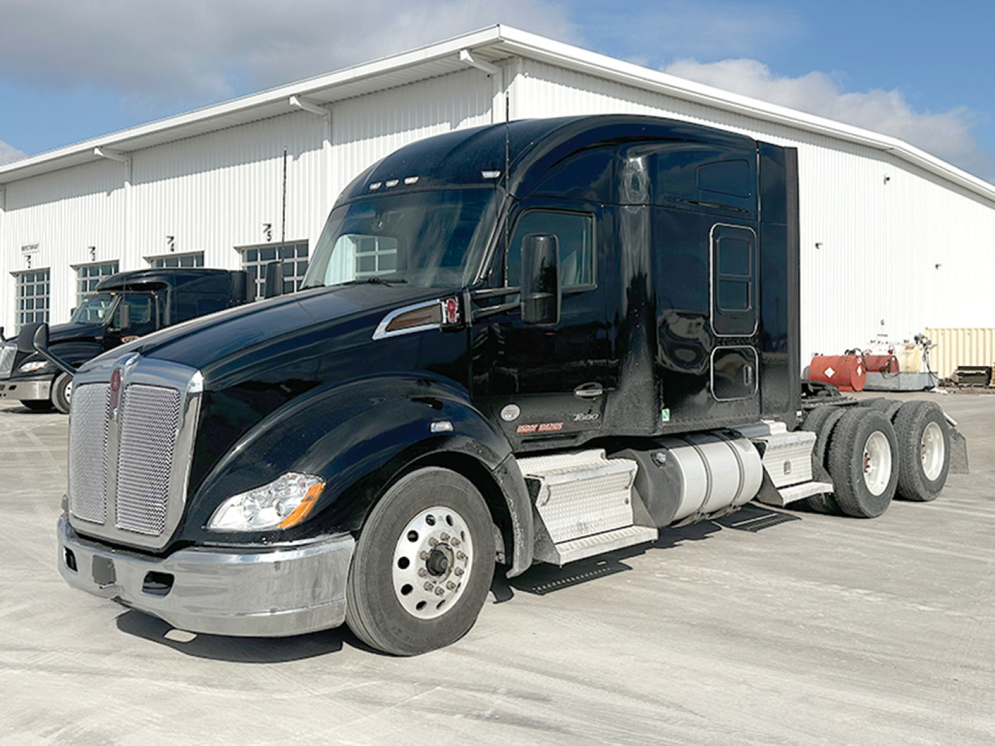 Kenworth T680 conventional sleeper tractor in dark blue, front-left view, with chrome bumper, silver fuel tanks, and tandem rear axles.