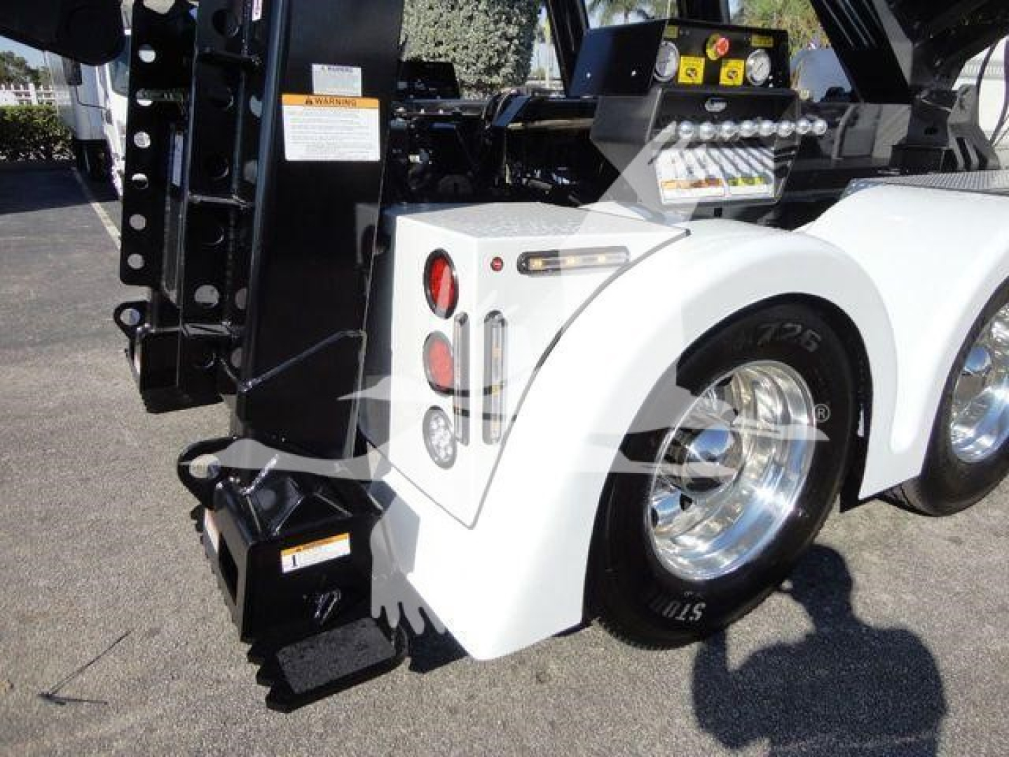Freightliner M2 106 rear wheel and winch mounting showing white fender, taillights, and hydraulic components.