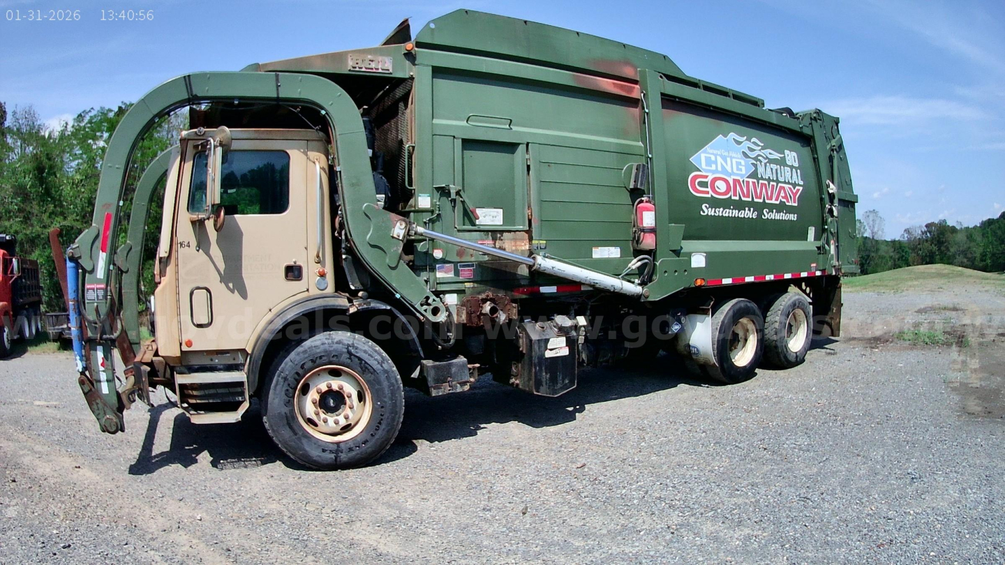 Truck body with green garbage compactor showing Conway Sanitation logo and side panels, Mack MRU613 chassis, front cab in tan