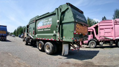 Truck rear and side view showing a green Mack MRU613 refuse truck with 'CONWAY' logo and caution signs, serving as a used equipment listing.