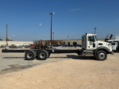 Mack GR64B truck chassis with long flatbed and triple-axle rear, white cab, stock number 71808, VIN tag not visible.