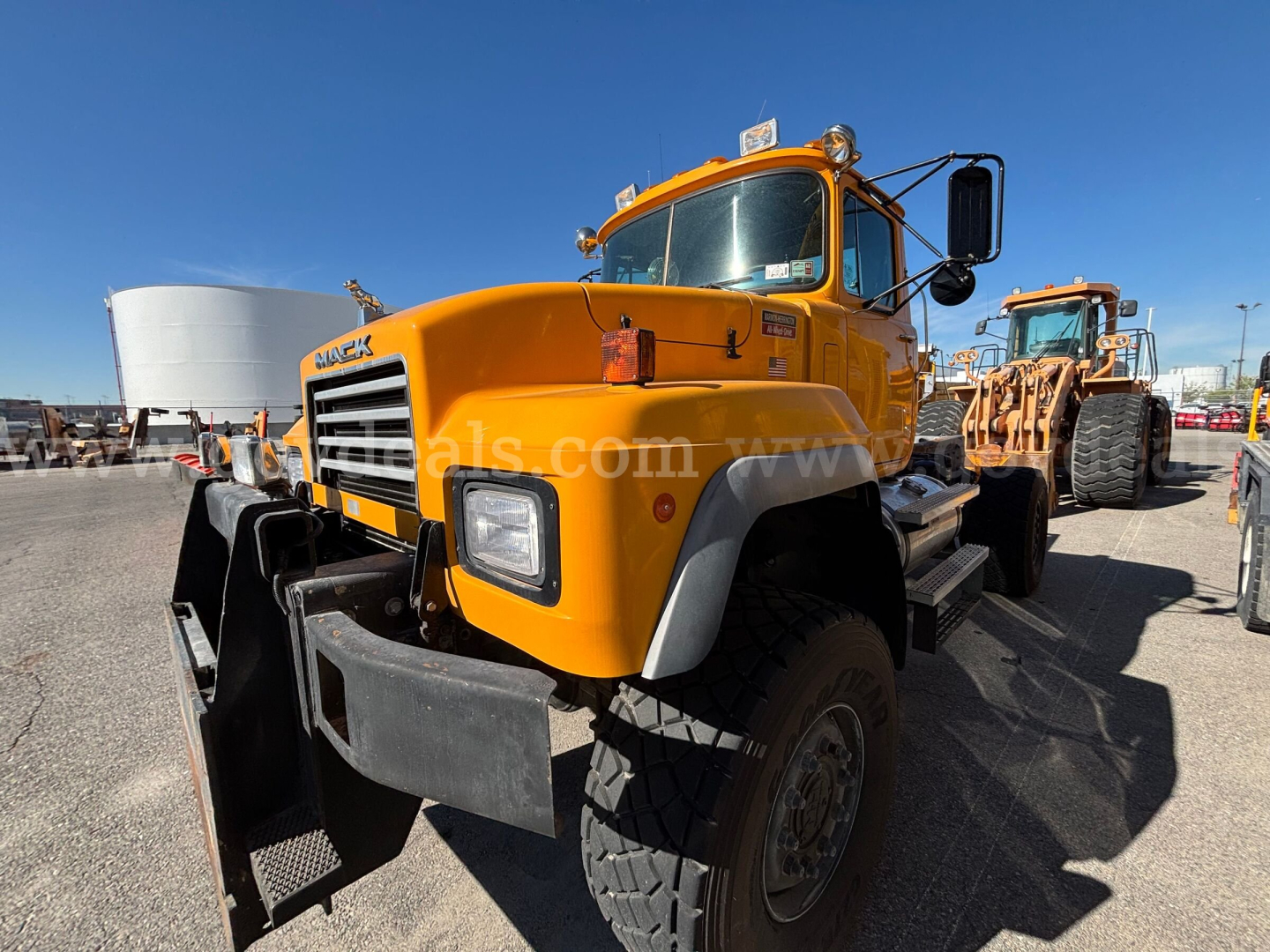 1996 Mack RD688P cab and chassis truck in yellow with front bumper and large tires, side view showing grille and dual headlights.