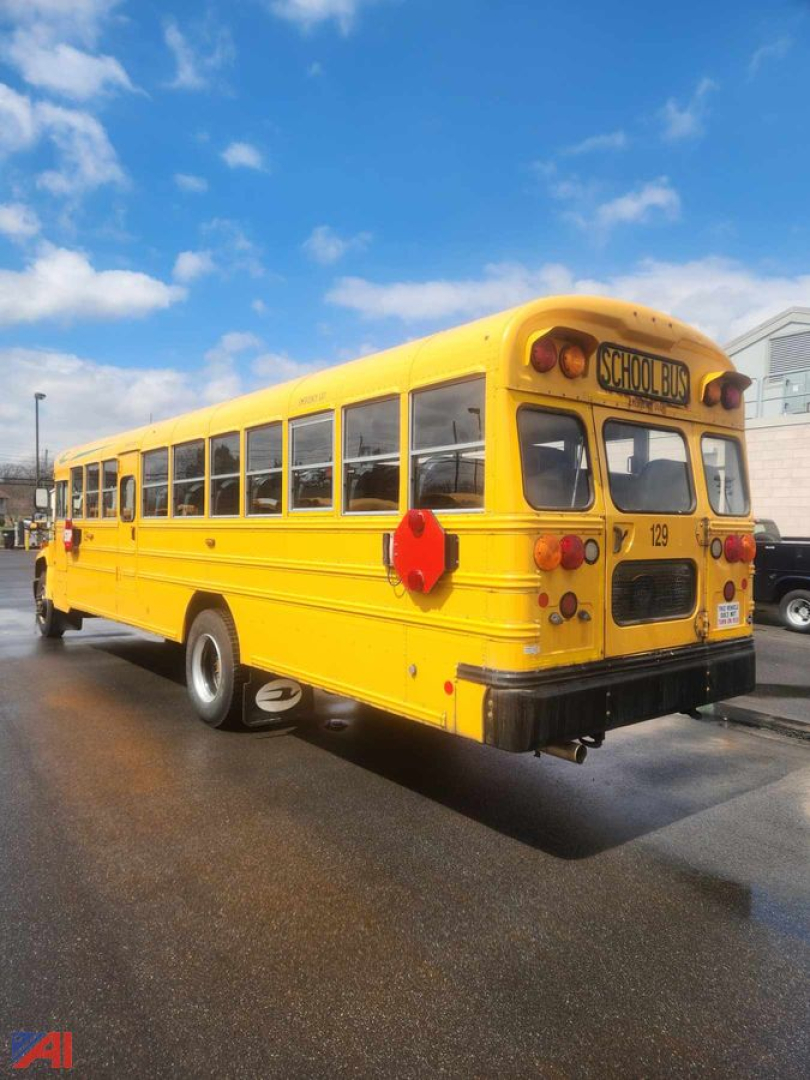 School bus rear and side view: yellow Blue Bird Vision bus with red circular stop sign on side, rear lights, and 'SCHOOL BUS' sign on top rear window area.