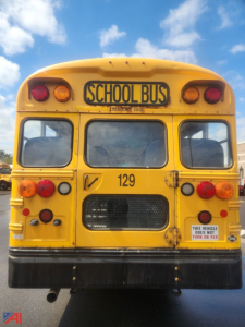 Back view of a yellow 2016 Blue Bird Vision school bus with 'SCHOOL BUS' sign, rear lights, number 129, and a black bumper.