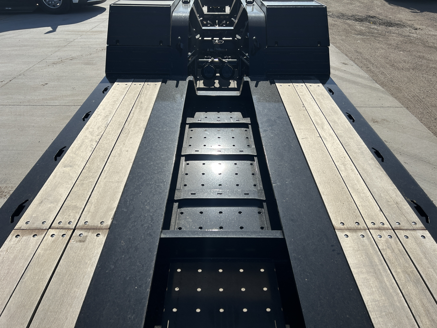 Trailer deck of a new Load King lowboy trailer showing dual aluminum deck ramps, center structural frame, and mounting hardware; 8'-6" deck width and heavy-duty suspension visible.