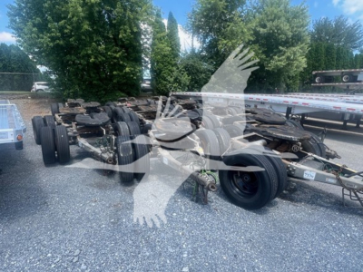 Trailer dolly chassis showing multiple axles and wheels with tires, winches, and metal frame; faint watermark of overlapping hands across image.